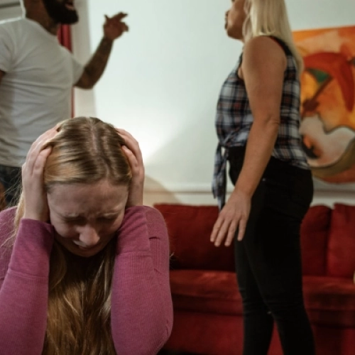 Girl crying with parents arguing in background